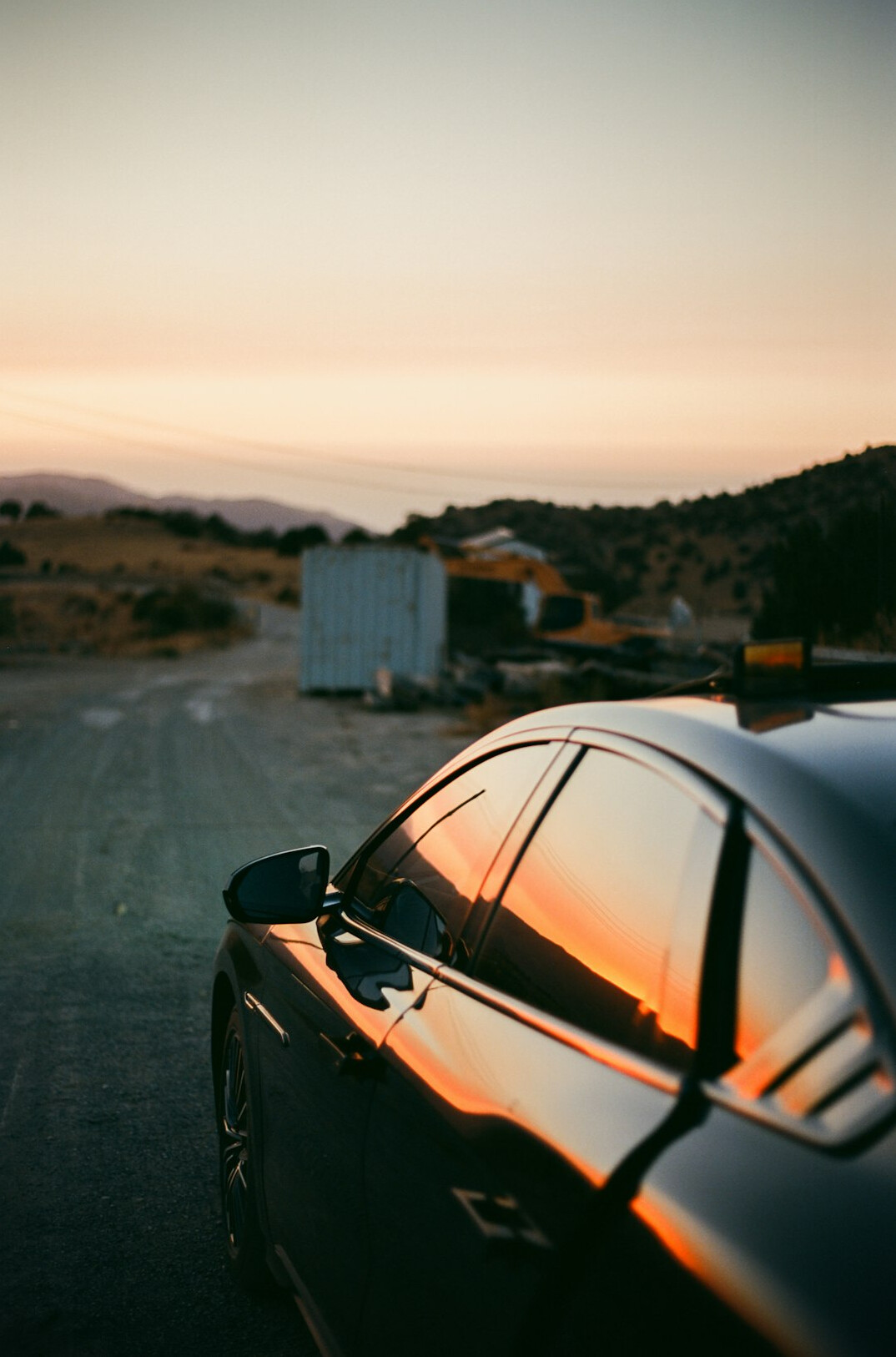Sports car parked on a road at sunset